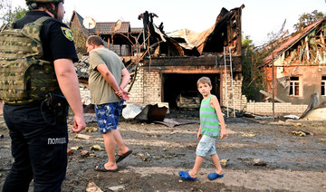 People walk by a house destroyed by shelling by multiple launch rocket systems in Kharkiv on July 7, 2022. (AFP)